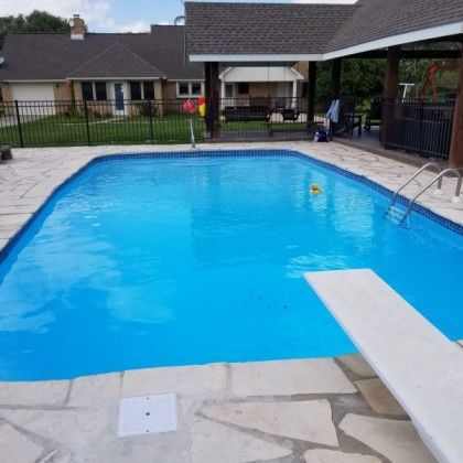A large swimming pool with a diving board in front of a house.