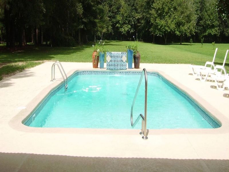A large swimming pool surrounded by chairs and trees