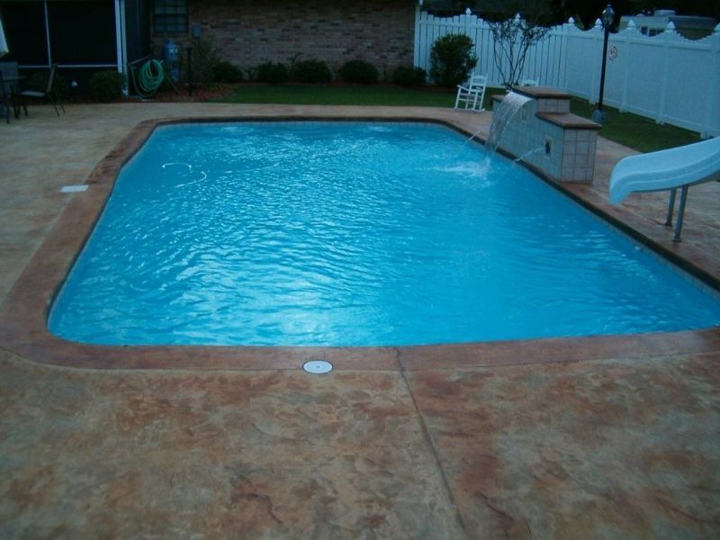 A large swimming pool with a slide in the backyard.