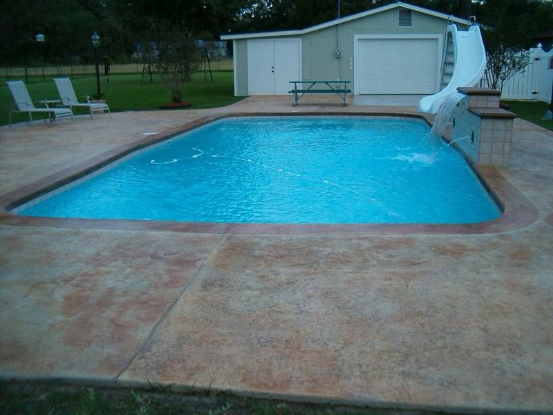 A swimming pool with a slide and a shed in the background