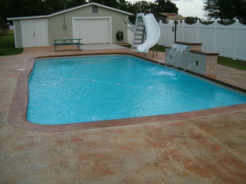 A large swimming pool with a slide in the backyard