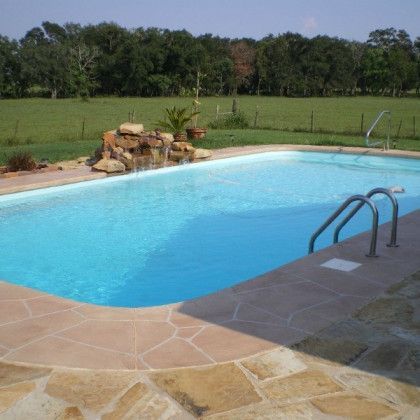 A large swimming pool surrounded by grass and trees