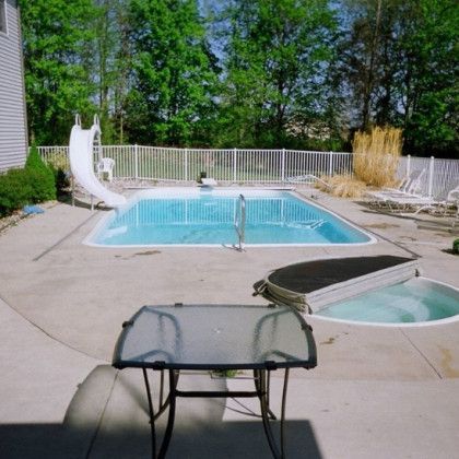 A swimming pool with a slide and a table in front of it