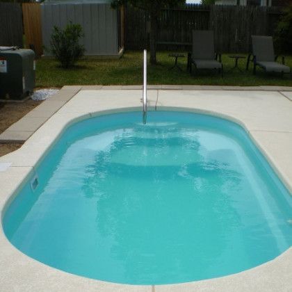 A small swimming pool in a backyard with chairs and a fence in the background