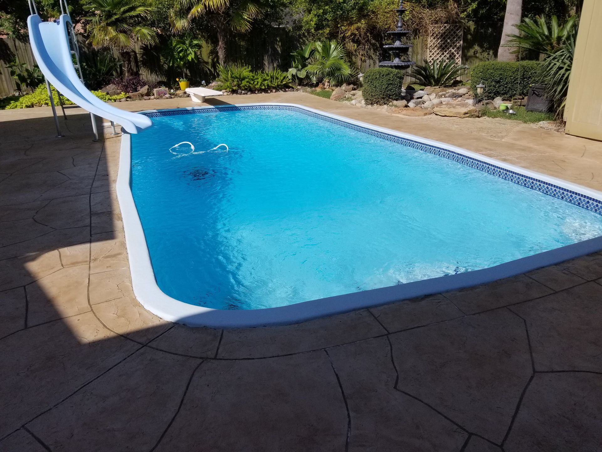 A large swimming pool with a slide in the backyard.