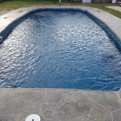 A large swimming pool filled with blue water in a backyard.