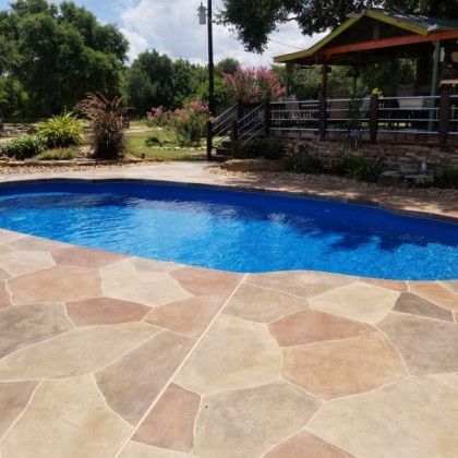 A large swimming pool surrounded by a stone patio and a gazebo.