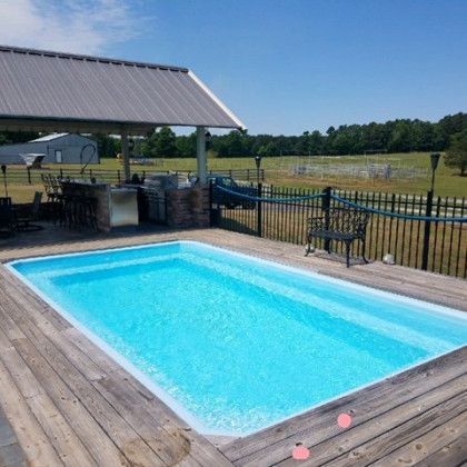 A large swimming pool is sitting on top of a wooden deck.