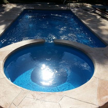 A large swimming pool with a hot tub in the middle