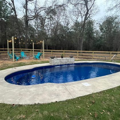 There is a large swimming pool in the backyard with a wooden fence surrounding it.