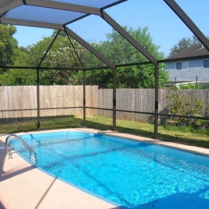 A screened in swimming pool with a wooden fence in the background