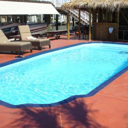 A large swimming pool surrounded by chairs and a thatched hut