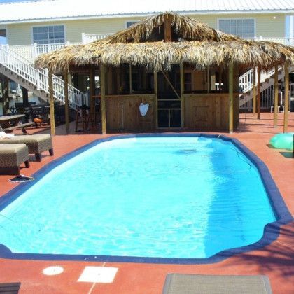 A large swimming pool with a thatched hut in the background