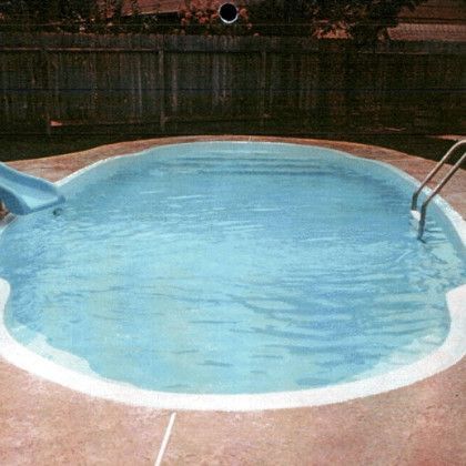 A small swimming pool with a slide in the backyard.