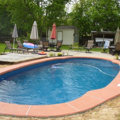 A swimming pool surrounded by chairs umbrellas and a table