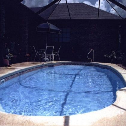 A large swimming pool with a table and chairs in the background