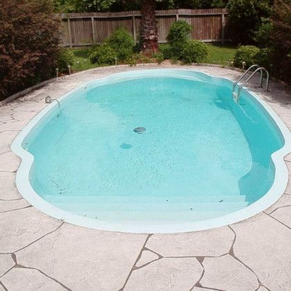 A large oval shaped swimming pool with a fence in the background
