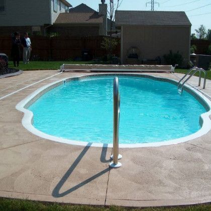 A large swimming pool in a backyard with people standing around it