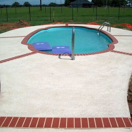 A large swimming pool is surrounded by a brick walkway