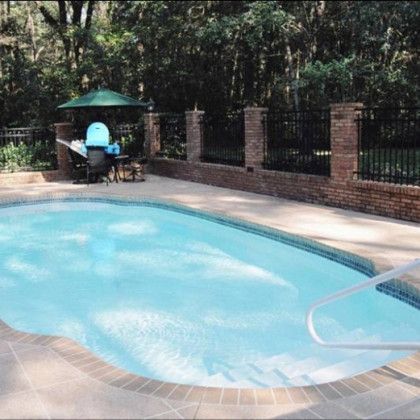 A large swimming pool surrounded by trees and a fence