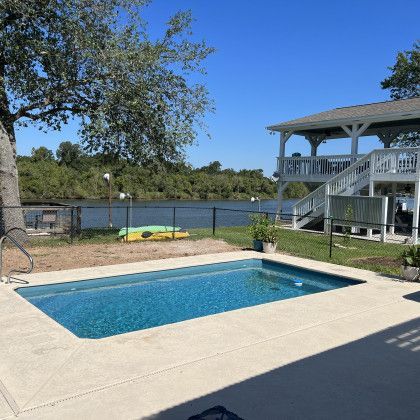 A large swimming pool with a house in the background