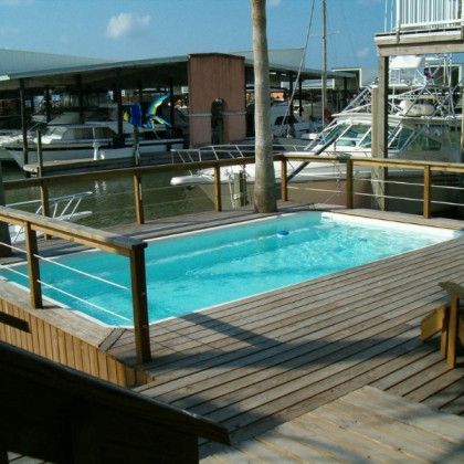 A large swimming pool is surrounded by a wooden deck