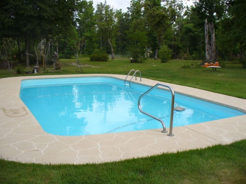 A large swimming pool in the middle of a lush green field
