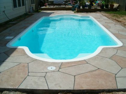 A large swimming pool is sitting on top of a stone patio.