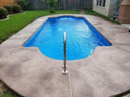 A small swimming pool in the backyard of a house.