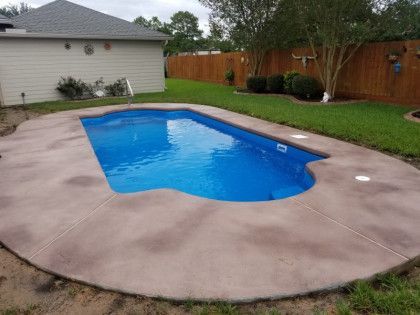 A large swimming pool is in the backyard of a house.
