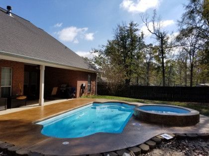 A large swimming pool with a hot tub in the backyard of a house.