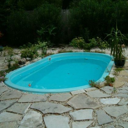 A small blue swimming pool surrounded by rocks and plants