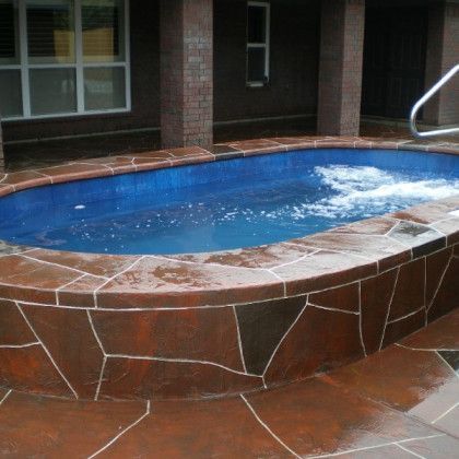 A large swimming pool is surrounded by a stone wall