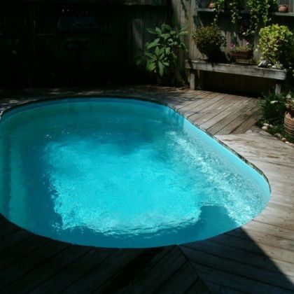 A small swimming pool is sitting on a wooden deck