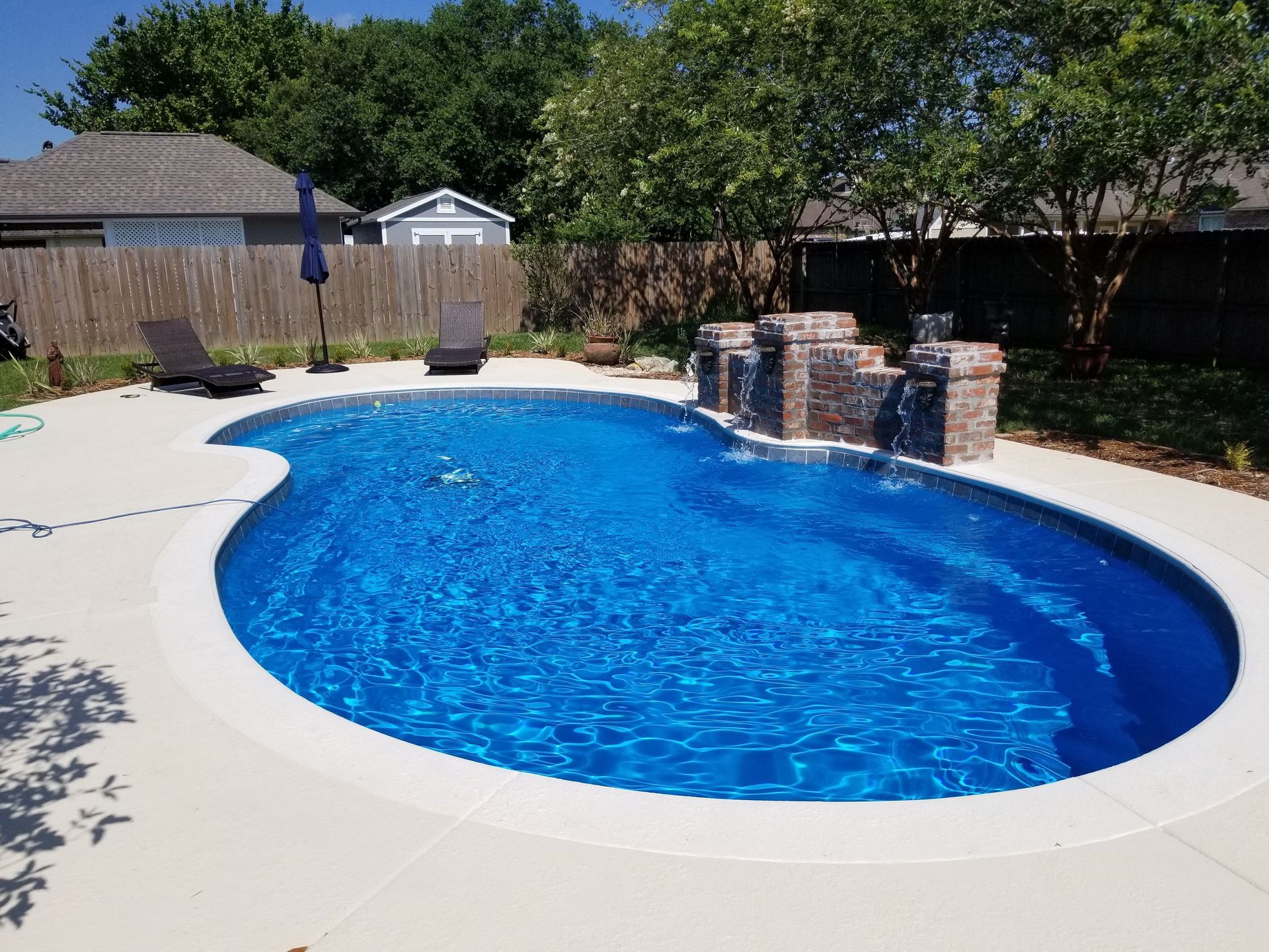 A large oval swimming pool with a waterfall in the backyard