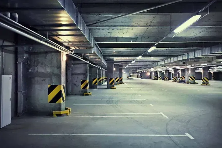 An empty underground parking garage with a lot of parking spaces.