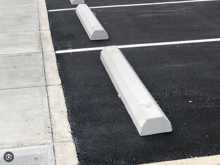 A parking lot with concrete curbs on the side of it