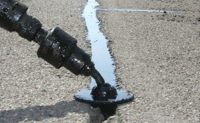 A person is pouring liquid into a hole in the ground.