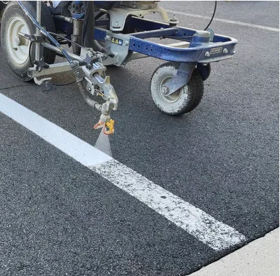 A machine is painting a white line on the road