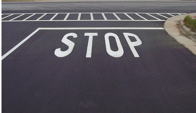 A stop sign is painted on the side of the road