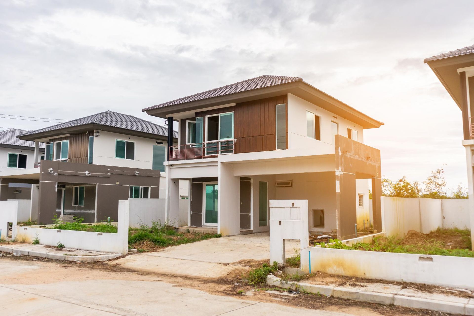 Two modern two-story houses in a quiet suburban neighborhood at sunset