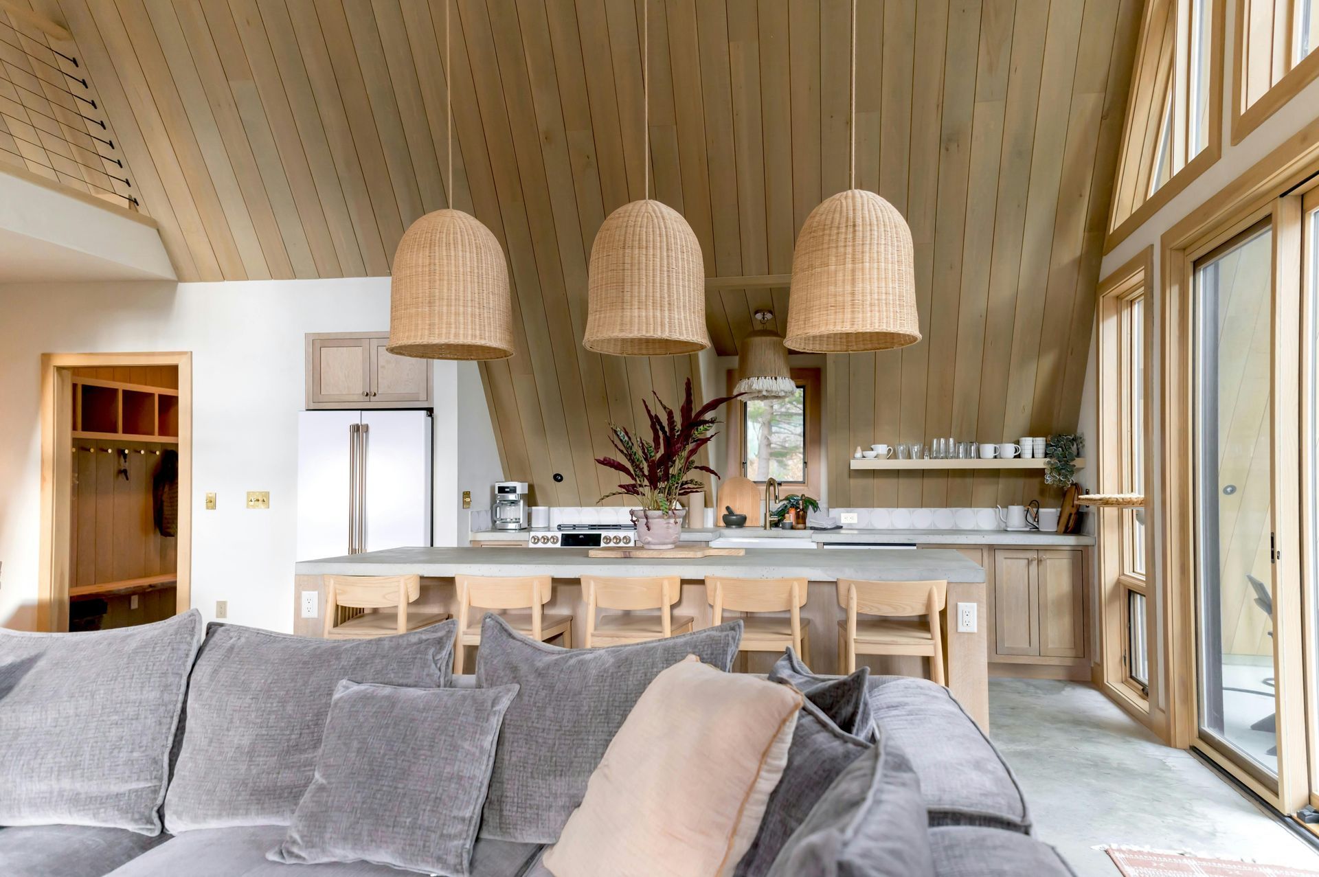 Modern open-concept living and dining room with a staircase, neutral decor, and warm kitchen lighting