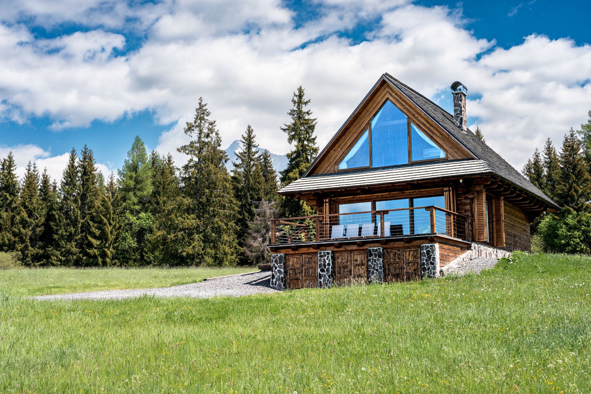 Modern luxury house at dusk with glass walls, pool, and outdoor lounge under a pergola