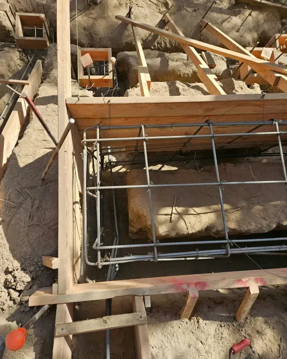 Construction site with wooden framing and rebar cage set in a trench.
