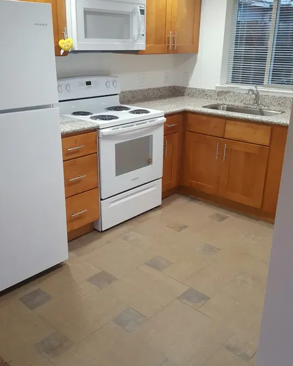 Kitchen with white appliances, wooden cabinets, and granite countertops.