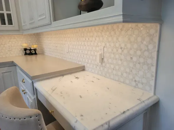 Kitchen countertop with hexagonal tile backsplash and built-in desk area.
