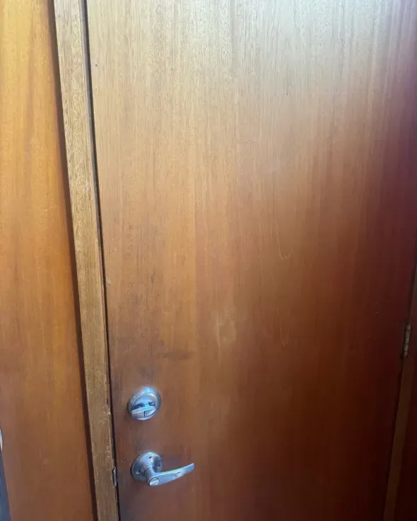 Wooden door with a doorknob and lock, in a room.