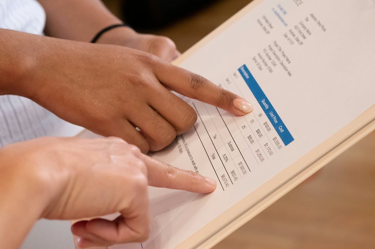 Two hands pointing to a printed form with a blue highlighted section on a desk
