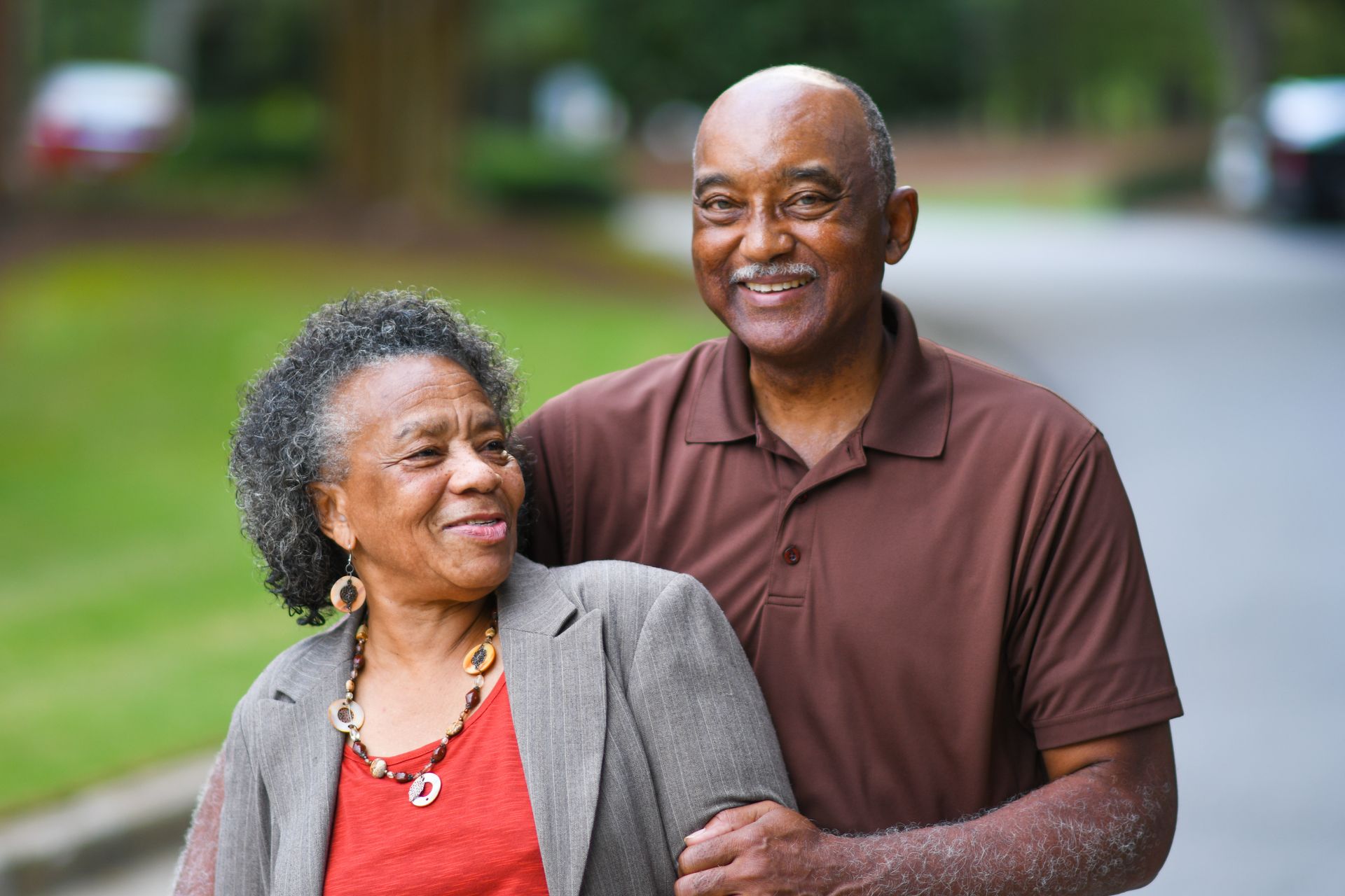 A man and a woman are standing next to each other on a sidewalk.
