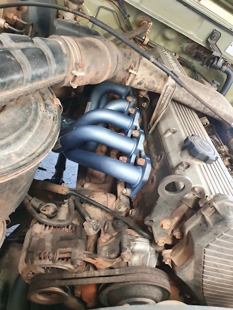 A Close up Of a Car Engine with A Blue Exhaust Pipe — Carline Automotive Solutions in Bungalow, QLD